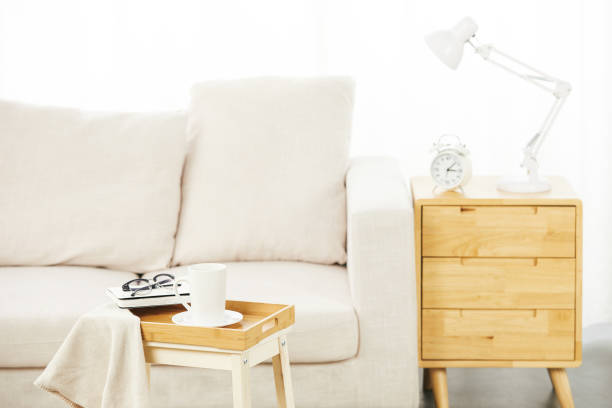 istock White sofa with small tables near it with a lamp, clock alarm, and personal objects on them 1441846986