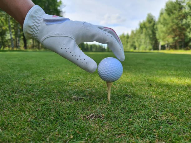 tient à la main une balle de golf avec tee sur le terrain de golf - golf golf course swinging isolated photos et images de collection