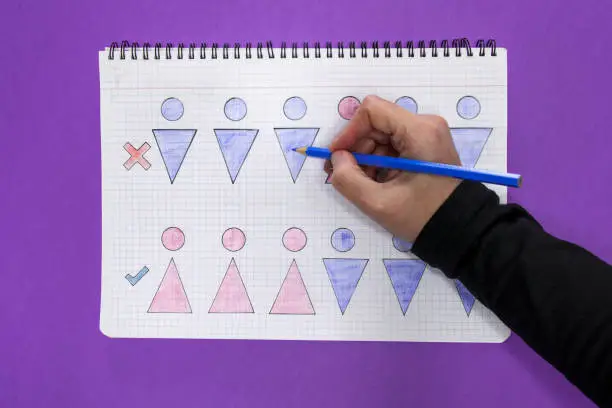 A notebook with drawings representing inequality/equality between men-women and a hand drawing them