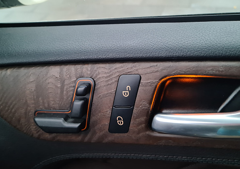Car door lock switch inside luxury car interior with leather and wood design concept