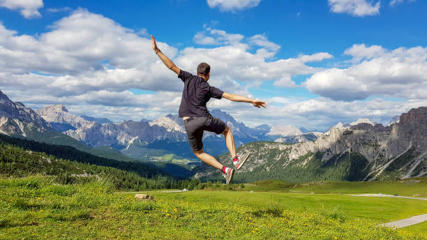 istock Hiker jumping up on the grass-covered meadow overlooking the mountains 1441847535