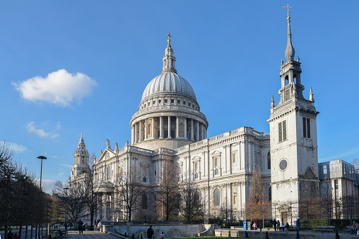 Color image depicting a crowd of people, thrown into silhouette and therefore unrecognisable, walking alongside modern futuristic architecture of glass and steel. In the distance we can see the ancient and iconic dome of St Paul's cathedral. Room for copy space.