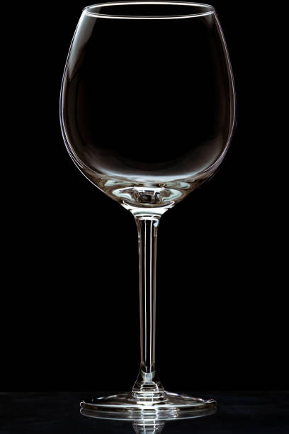 istock Vertical closeup of an empty wineglass on a reflective surface isolated on a black background 1441848742