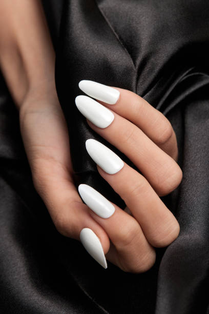 istock Female hand with long white nails holding a black satin fabric 1441849835