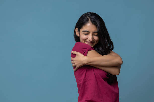 istock Mexican Latin female hugging herself tightly on a blue background 1441850064
