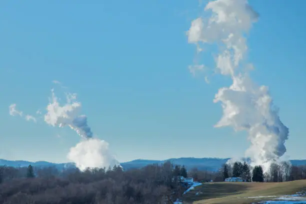 Smokestack emissions from coal-fired powerplants photographed against a rural West Virginia backdrop under a clear blue sky