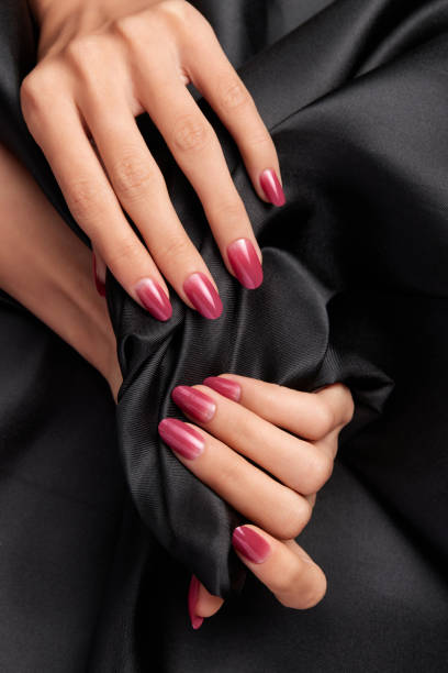 istock Female hands with pink nails holding a black satin fabric 1441850204