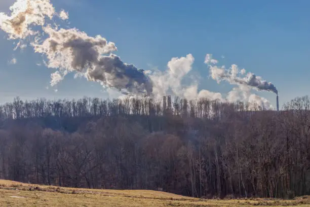 Smokestack emissions from coal-fired powerplants photographed against a rural West Virginia backdrop under a clear blue sky
