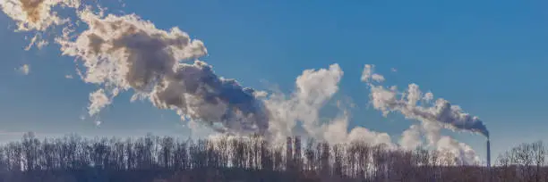 A panoramic shot of smokestack emissions from coal-fired powerplants photographed against a rural West Virginia backdrop under a clear blue sky