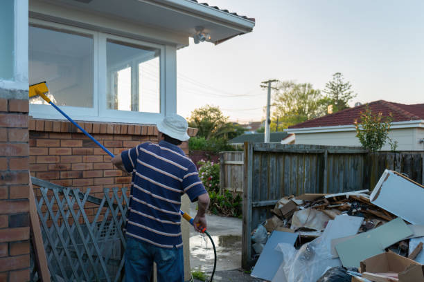 istock Man washing windows with long pole and brush. Construction rubbish from home maintenance piled in backyard. 1441852159