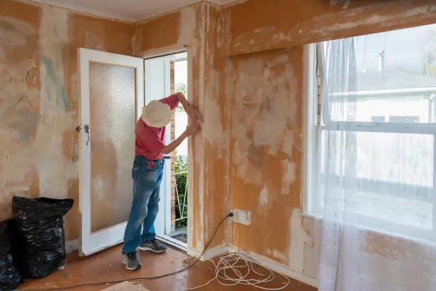 Man removing wallpaper inside an old house. Home renovation project.