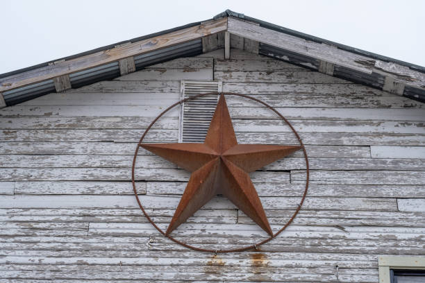 A red metal star, representing the Texas Lone Store, on a weather-beaten white painted wood house.