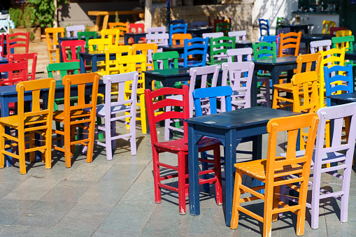 Street cafe in summer with color wooden vintage chairs and tables on a tourist street. Colored furniture and cafe design. High quality photo
