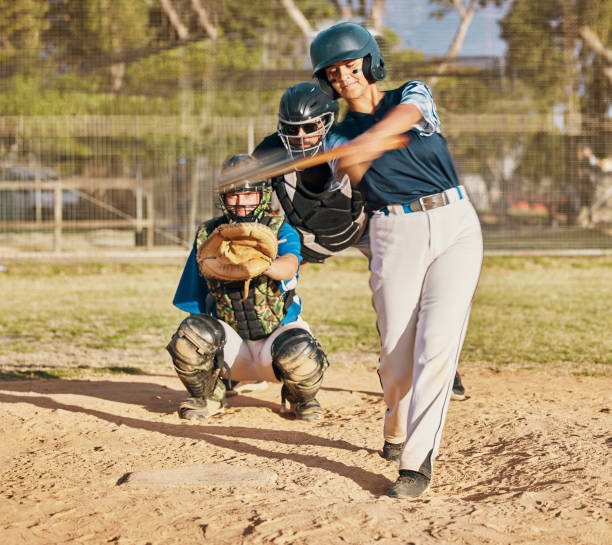 istock Baseball player, female athlete and swinging bat with sports technique or skill while playing a competitive game or match on a pitch or field. Fit female with a catcher doing exercise and recreation 1441860863