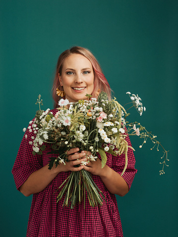 Beautiful woman with flowerbouquet studio shot against colorful background