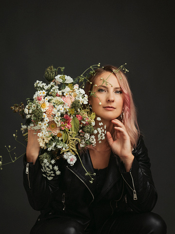Beautiful woman with flower bouquet studio shot\nPhotographed on dark grey studio background