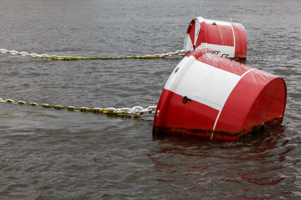 красно-белый причальный буй с цепью на водной глади. - buoy anchored sea wave стоковые фото и изображения