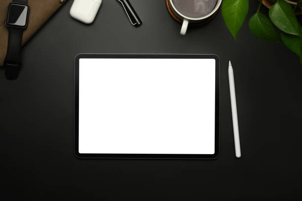 istock Digital tablet with white empty display, stylus pen, coffee cup and notepad on black wooden table. 1441864688