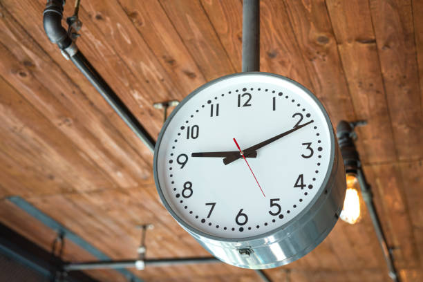 A classic style round clock which is installed on the wooden ceiling at the office place. Interior decoration and equipment object photo.