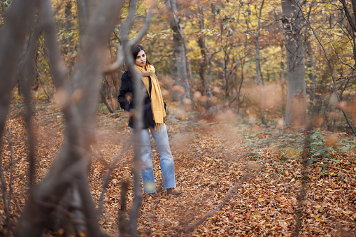 Happy young woman enjoying relaxing walk in beautiful autumn forest