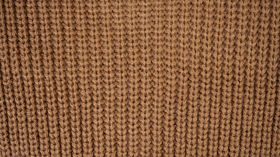 Texture of woolen knitwear.Natural woolen fabric, sweater fragment.Knitted pattern close-up.