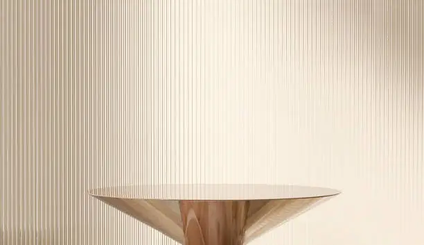Modern, minimal round gold colored steel table podium with reeded glass partition on cream colored wall Modern, minimal round gold colored steel table podium with reeded glass partition on cream colored wall