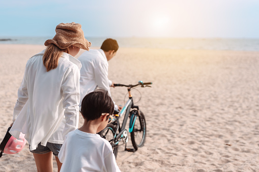 Family on the beach they are enjoy bicycle. Happy father, mother and son, daughter enjoying road trip the summer holidays.Parents and children are riding on a bicycle with a sea travel trip exercise