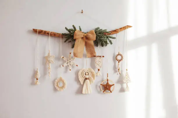 Christmas macrame decor. Christmas snowflake and decorative elements on wooden stick. Natural materials - cotton thread, wood beads. Eco decorations, ornaments, hand made decor. Copy space