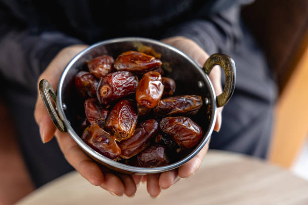 istock Young woman's hand offering dried dates in a cup 1441875317