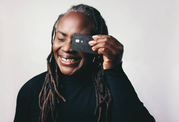 istock Cheerful woman with dreadlocks smiling while holding a credit card 1441875504