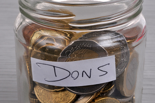 Coins in a clear glass jar with a label that says donations