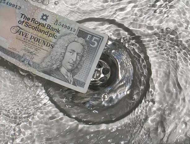 Scottish five-pound note 'floating'in a steel sink.