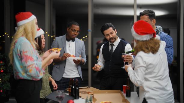 groupe d’hommes d’affaires multiraciaux appréciant de manger une pizza et de célébrer noël ensemble au bureau après le travail - after work beautiful people beer beer bottle photos et images de collection