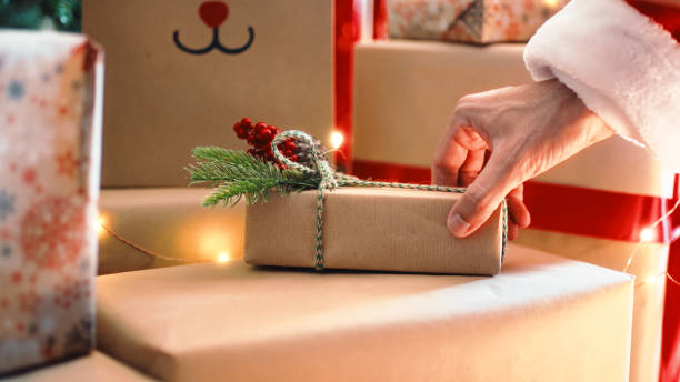 Santa Claus is placing the Christmas gift box under the tree