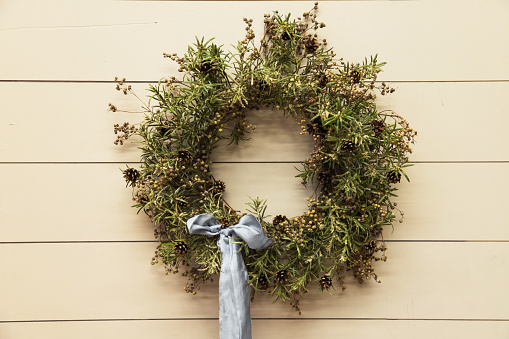 Christmas wreath made of fir branches hanging on a gray wall. New year and winter holidays