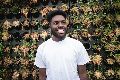 Portrait of a young, smiling African-American man in front of the vertical garden