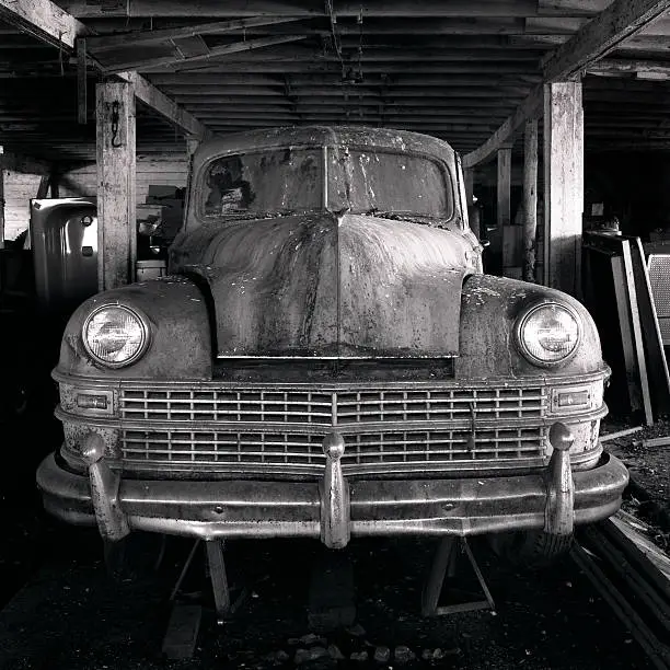 An old buick car left in a barn at an old farm house.