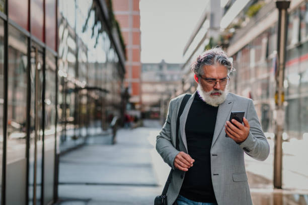 istock Senior businessman standing outside and using smartphone 1441881180