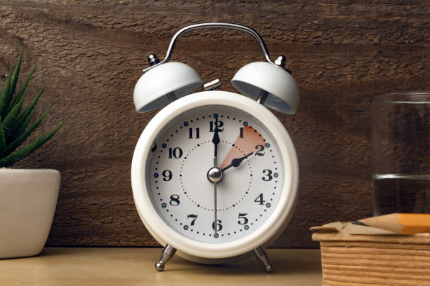 istock Daylight saving time concept: an alarm clock placed on a bedside table with an indication to move the hands backward 1441881247