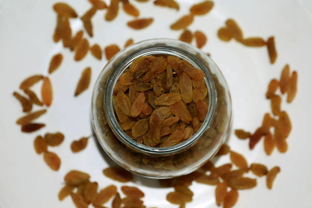 Glass bowl filled with fresh Raisins table top view with selective focus.