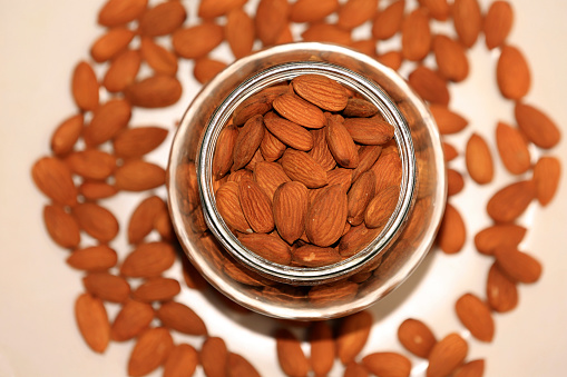 Glass bowl filled Almonds table top view with selective focus.
