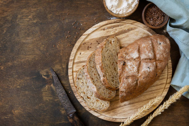 istock Bread from whole wheat grains, wheat bran, seeds, bio-ingredients over rustic table background. Homemade baking,  healthy lifestyle. View from above. Copy space. 1441883085