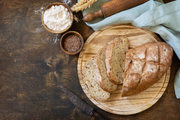istock Homemade baking. Bread from whole wheat grains, wheat bran, seeds, bio-ingredients over rustic table background, healthy lifestyle. View from above. Copy space. 1441883094
