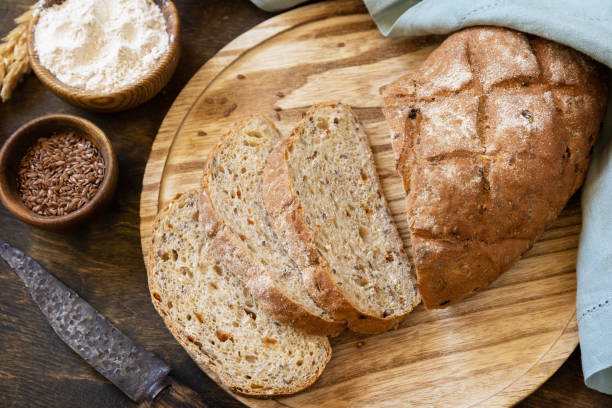 istock Bread from whole wheat grains, wheat bran, seeds, bio-ingredients over rustic table background. Homemade baking,  healthy lifestyle. 1441883117