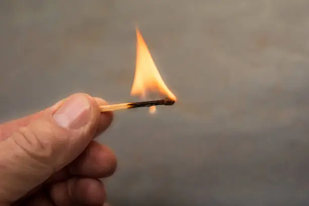 Male hand holding burning match stick