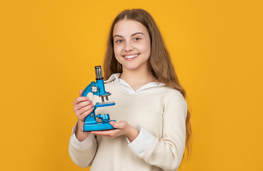 happy child with microscope on yellow background.