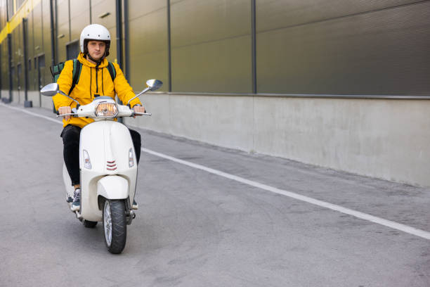 Caucasian man, an delivery person, driving scooter, while delivering the orders around the city