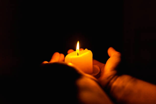 istock Burning candles in the boy hands on a dark background.Religious concept. 1441883860
