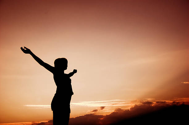 istock Woman standing with open arms as the sun sets 144188400