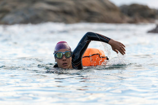 mulher que nada em águas abertas com roupa de mergulho e boia - boia equipamento de desporto aquático - fotografias e filmes do acervo